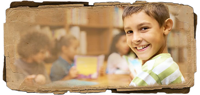 A boy smiling for the camera in a classroom